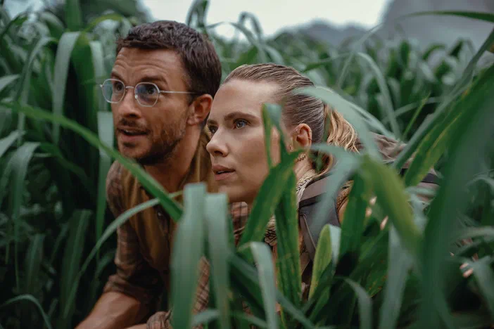 Dans un champ de maïs, deux personnages observent avec attention leur environnement dans le film Jurassic World : Rebirth