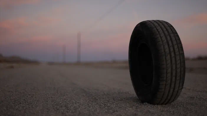 Un pneu de voiture se tient seul sur une route déserte au crépuscule.